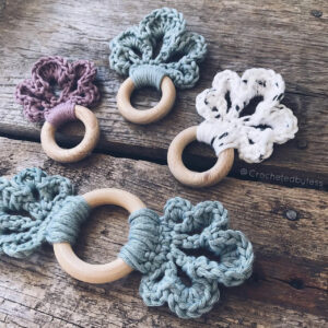 Four LoLo Loop Baby Teethers placed on a wooden backdrop in an angle