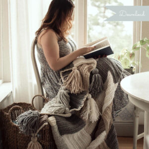 Tess sitting and reading infront of a window with the Stay Awhile Boho Blanket